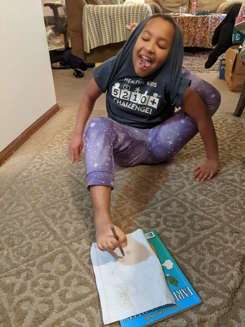 Irene drawing with one foot, other foot behind her back, Fort Collins, Colorado, 2022