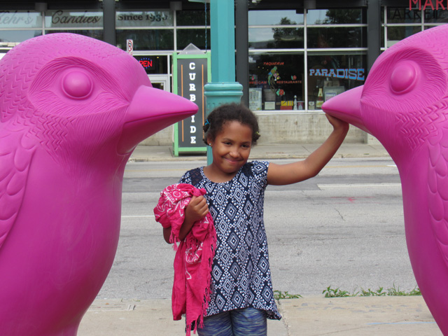 Irene between two pink birds at the market, Milwaukee, Wisconsin, 2021